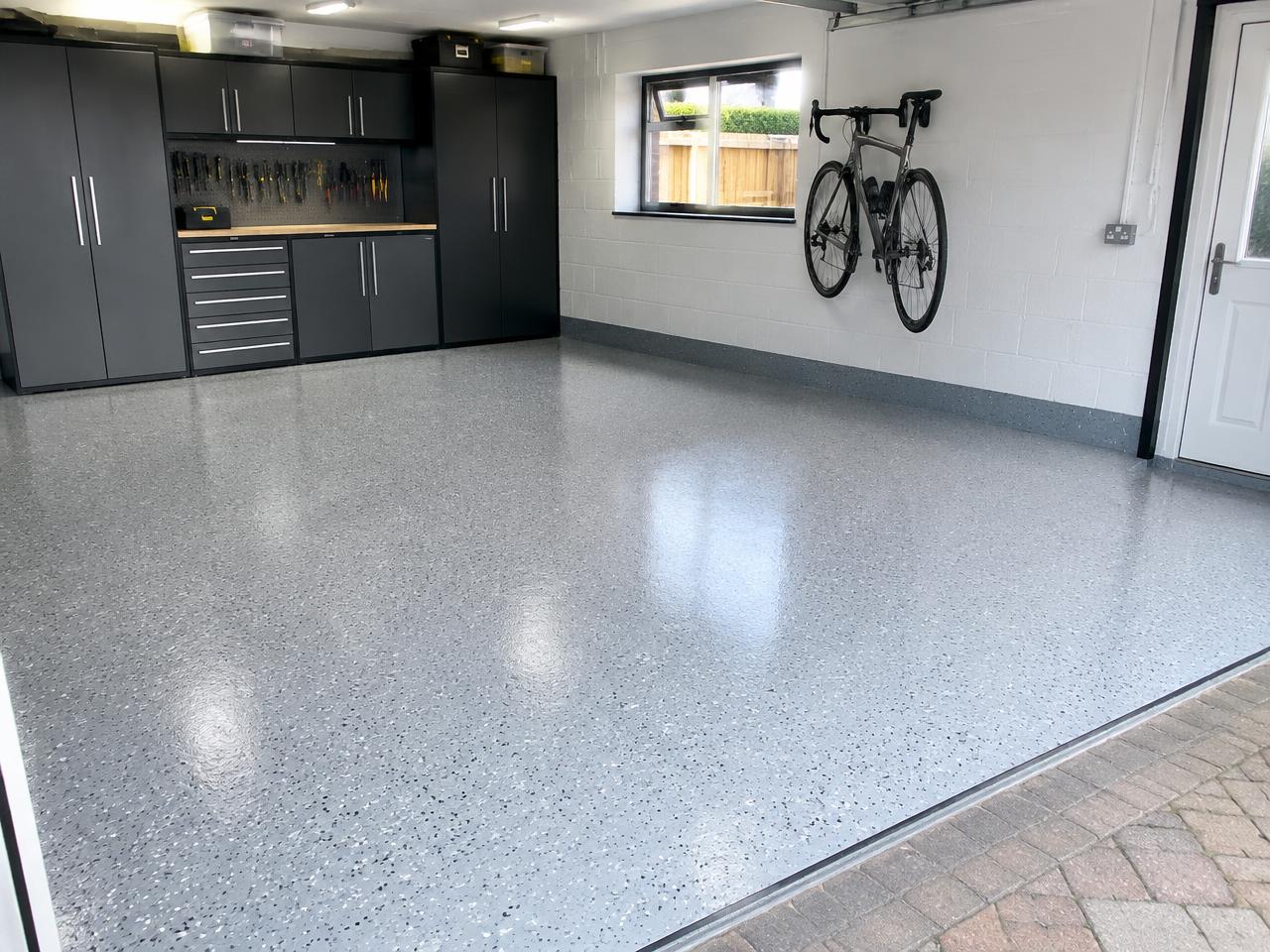 Restored garage floor after concrete repairs, finished in light flake resin
